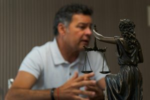 man sitting at a table with lady justice statue in front of him