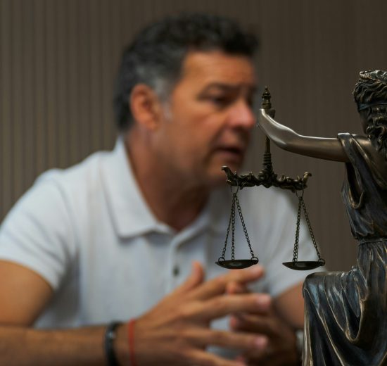 man sitting at a table with lady justice statue in front of him